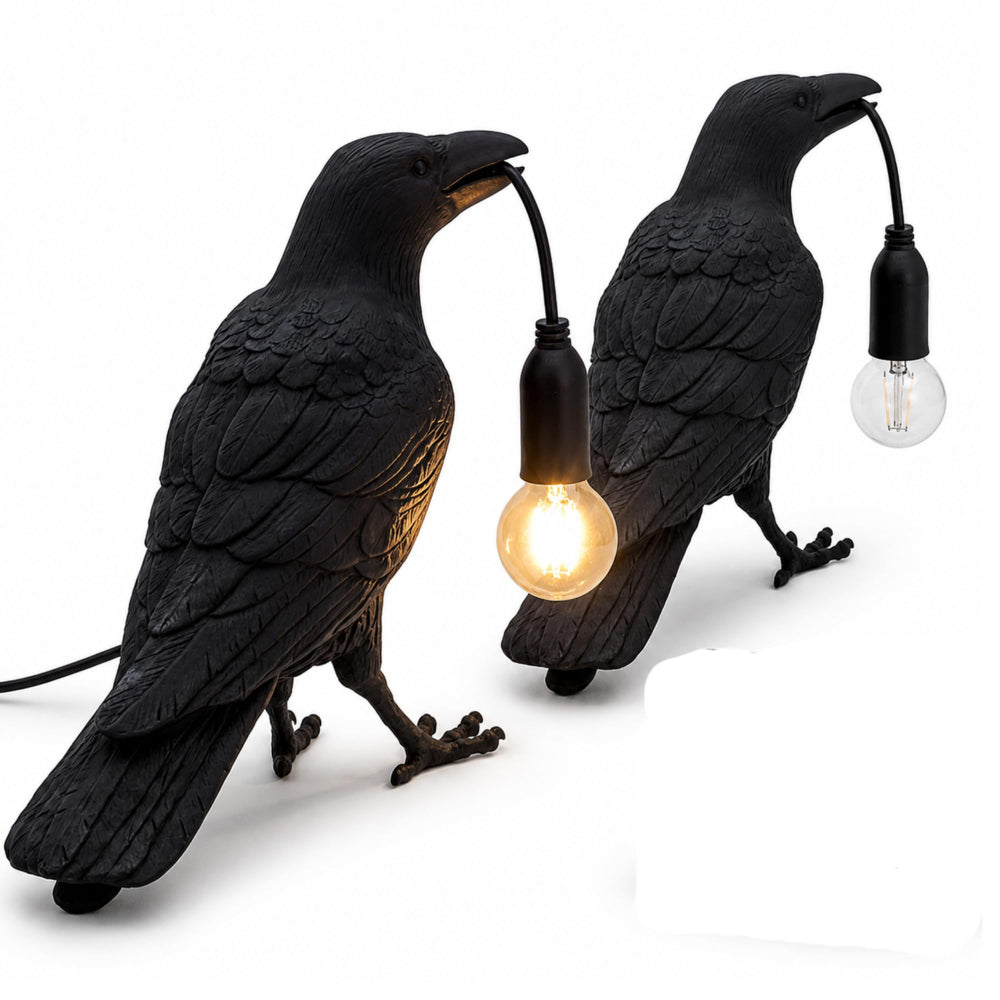 Black raven table lamp glowing warmly on a wooden bedside table